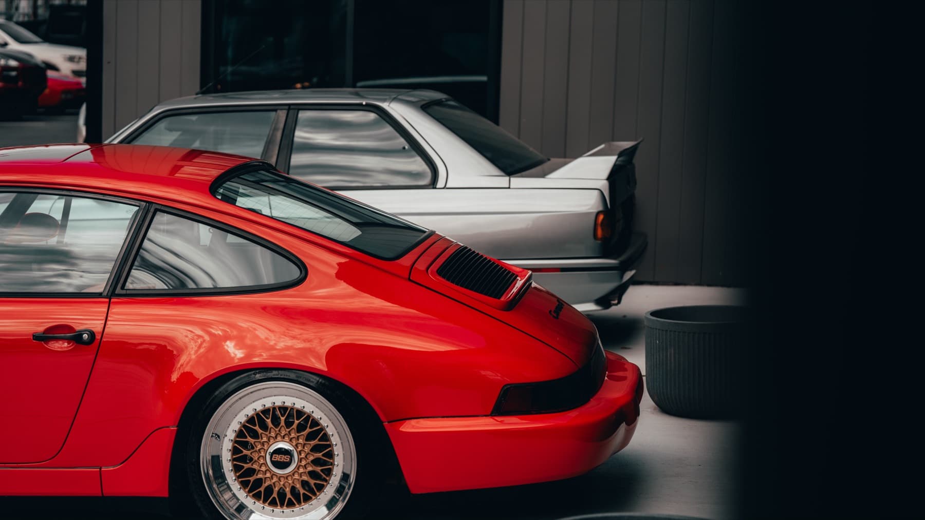 Orange classic Porsche 911 beside a BMW E30