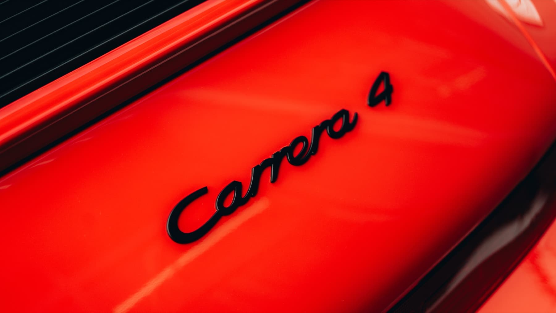Carrera 4 badge on an orange Porsche