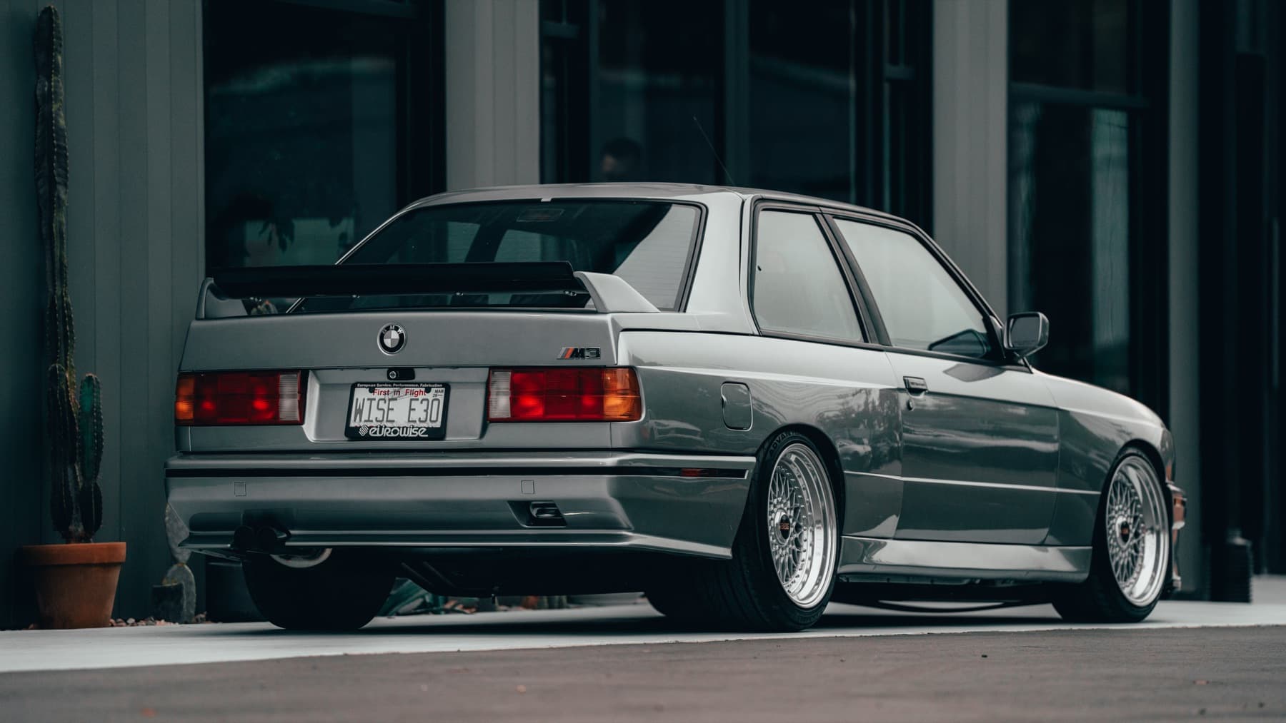 Rear three-quarter view of a silver BMW E30 M3