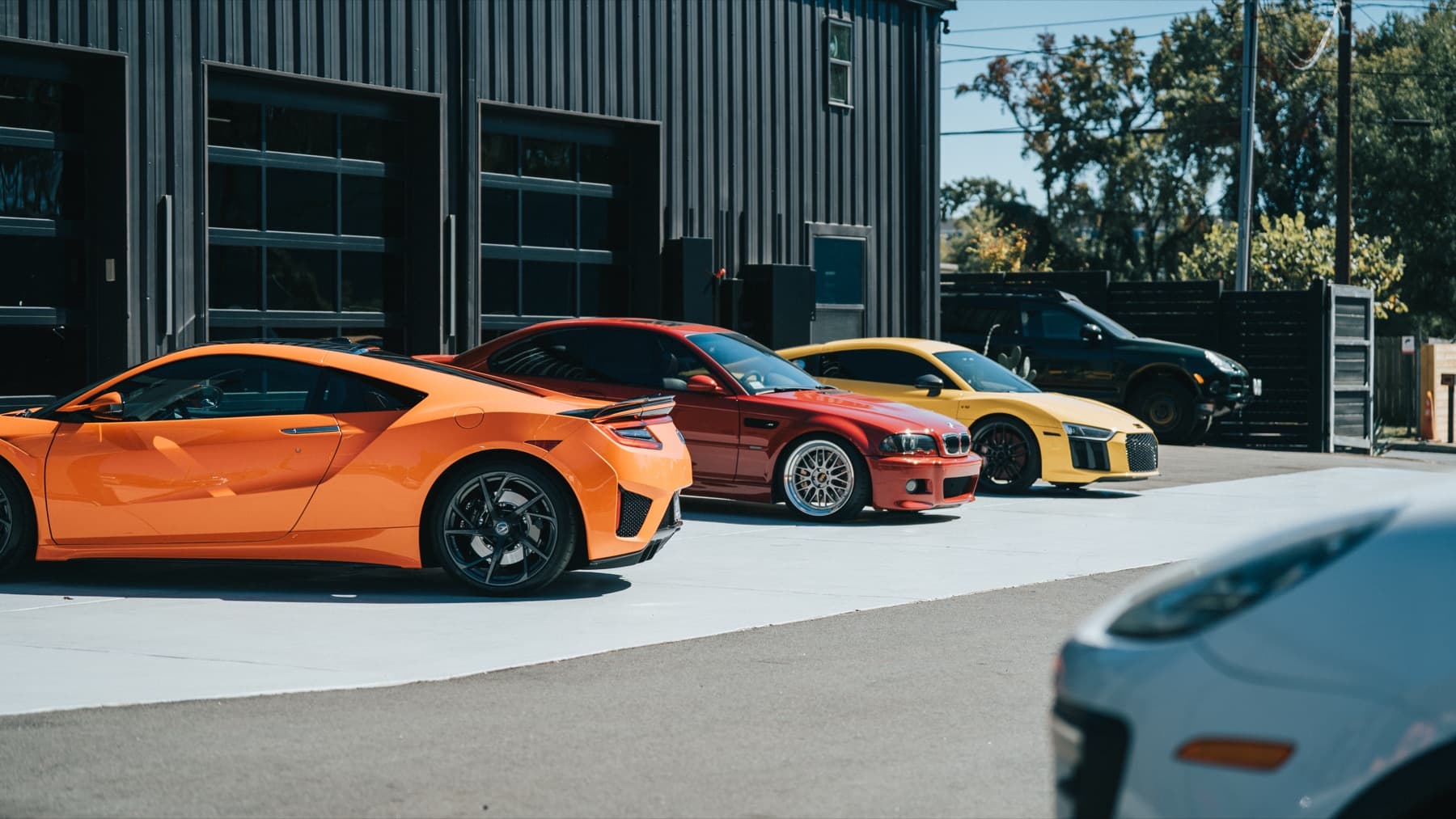 Orange and yellow sports cars lined up outside the shop