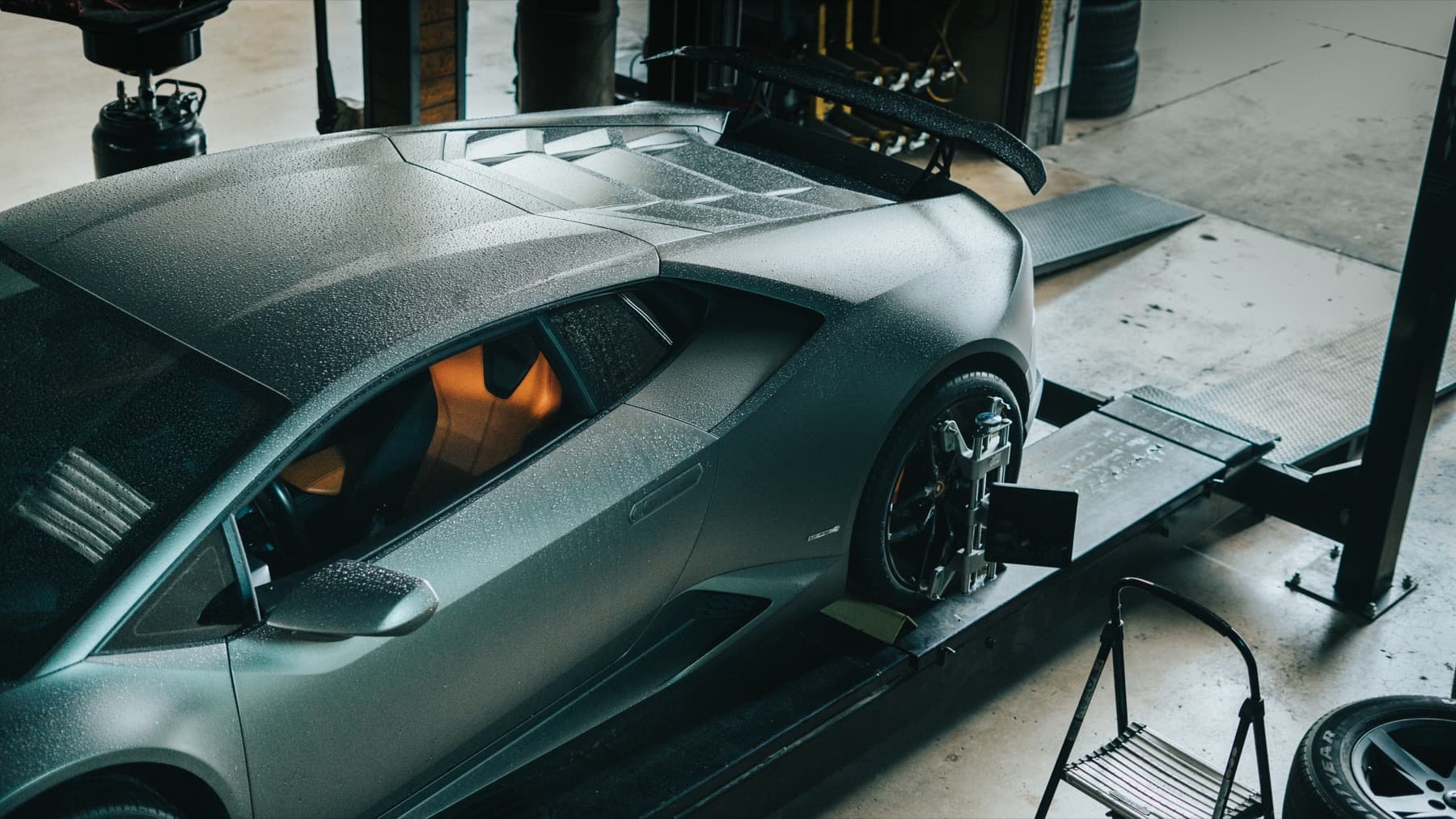 Grey Lamborghini Huracán in profile, wet from a wash