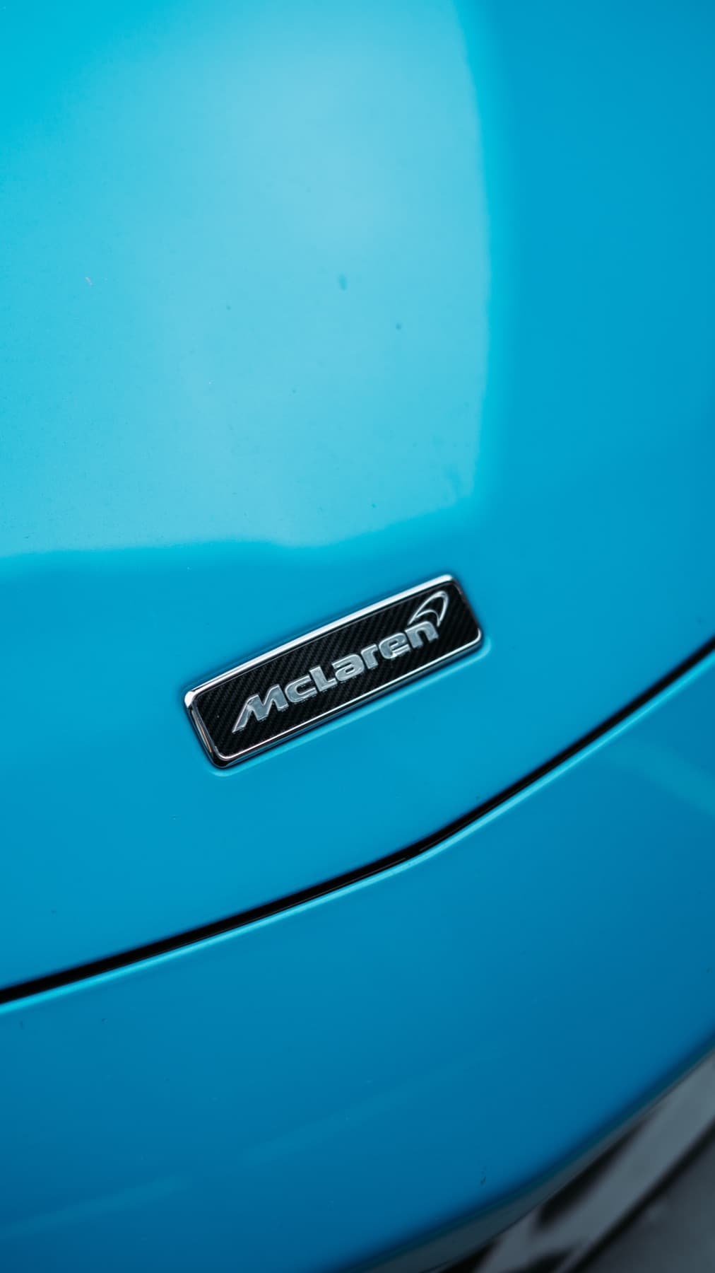 Badge detail on a light blue McLaren