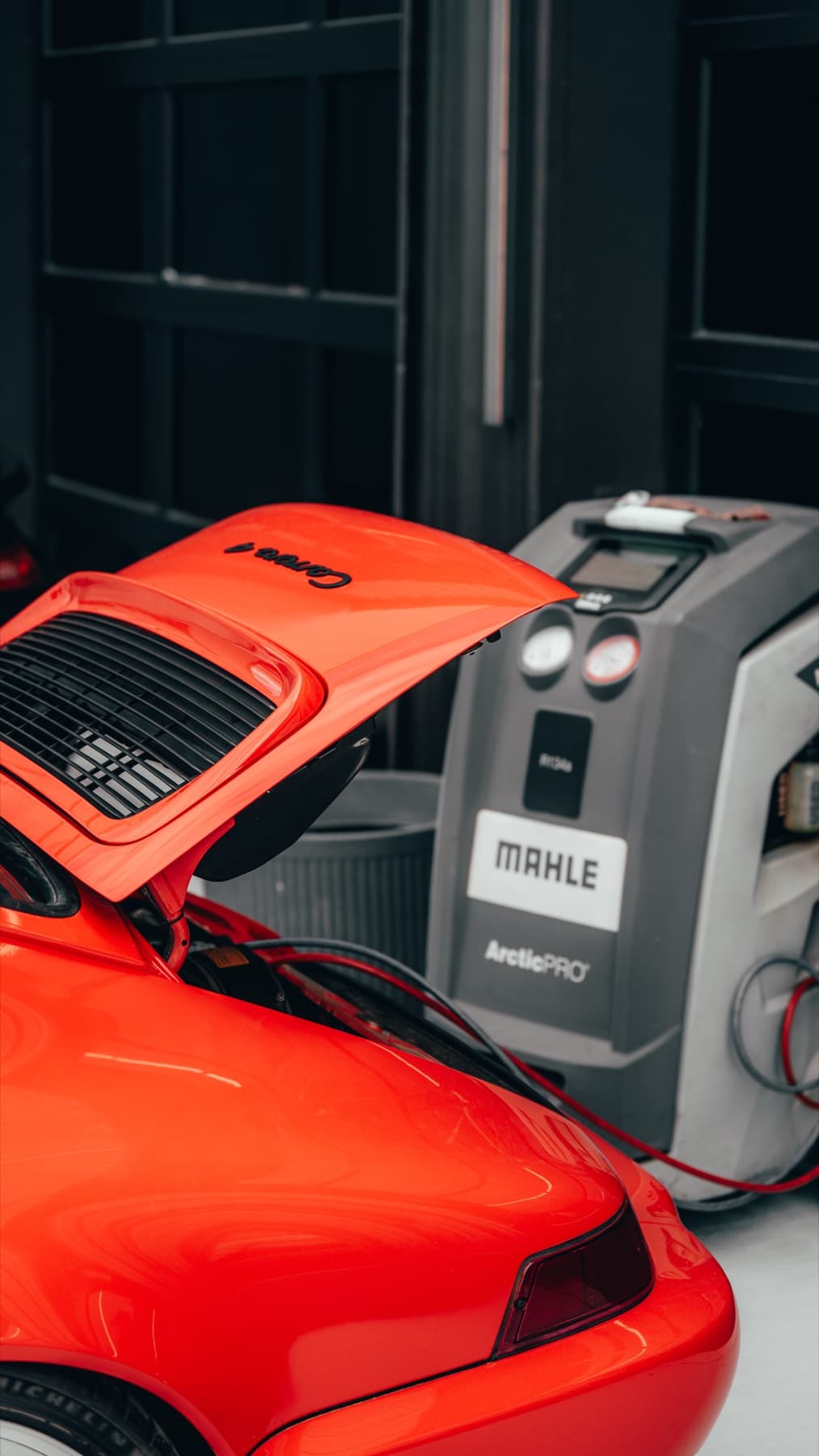 A/C service machine hooked up to an orange Porsche 911