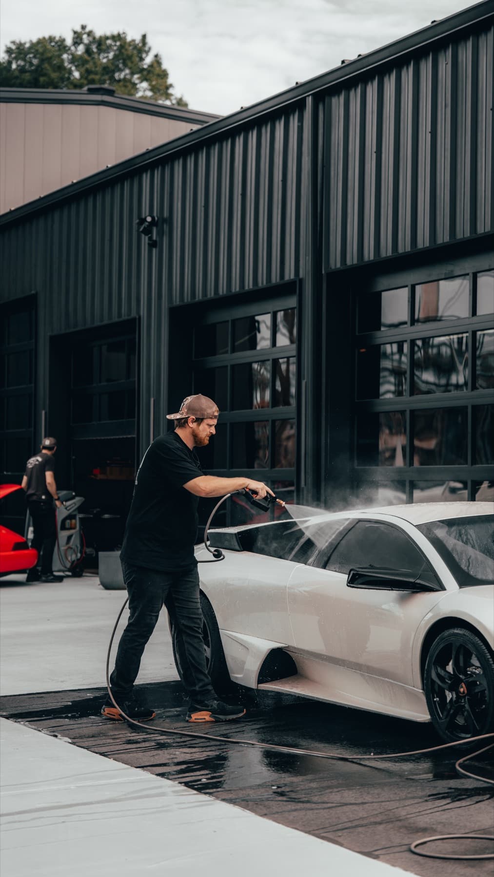 Technician with a white Porsche outside the shop