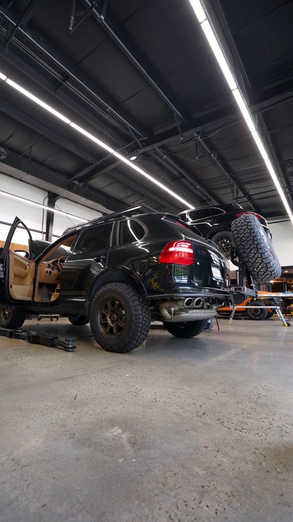Dark SUV on a lift with its wheels off
