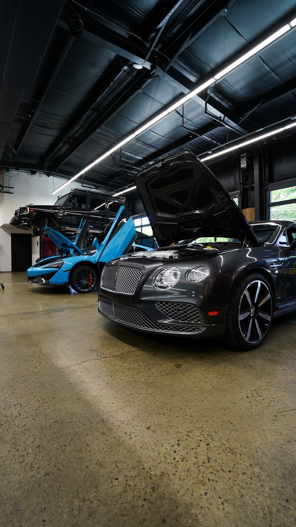 Blue McLaren and a dark Bentley in the service bays