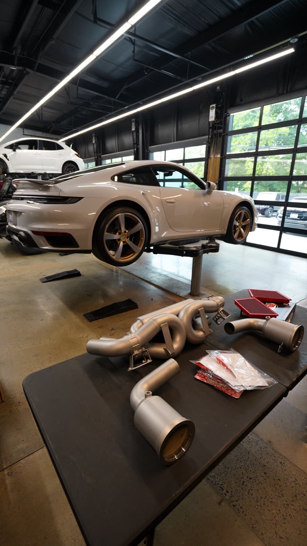 Silver Porsche 911 with exhaust parts laid out on a bench