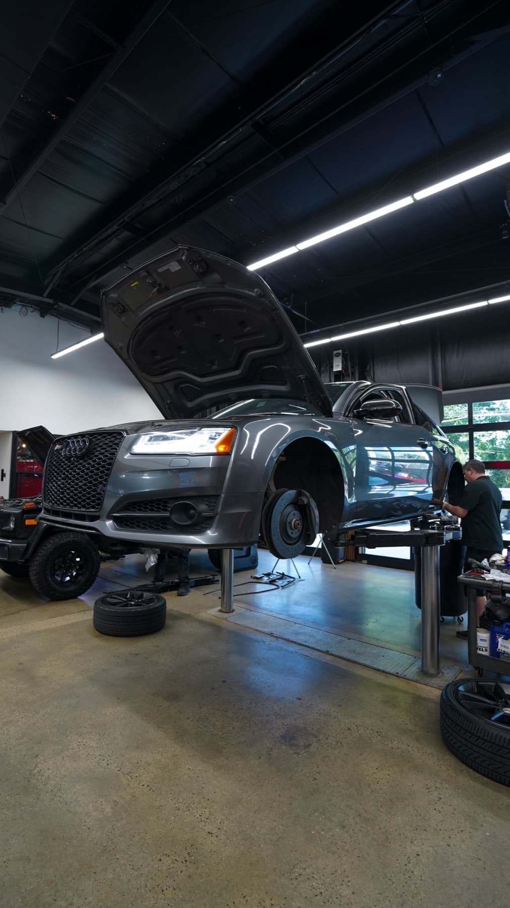SUV with its hood open and wheels off