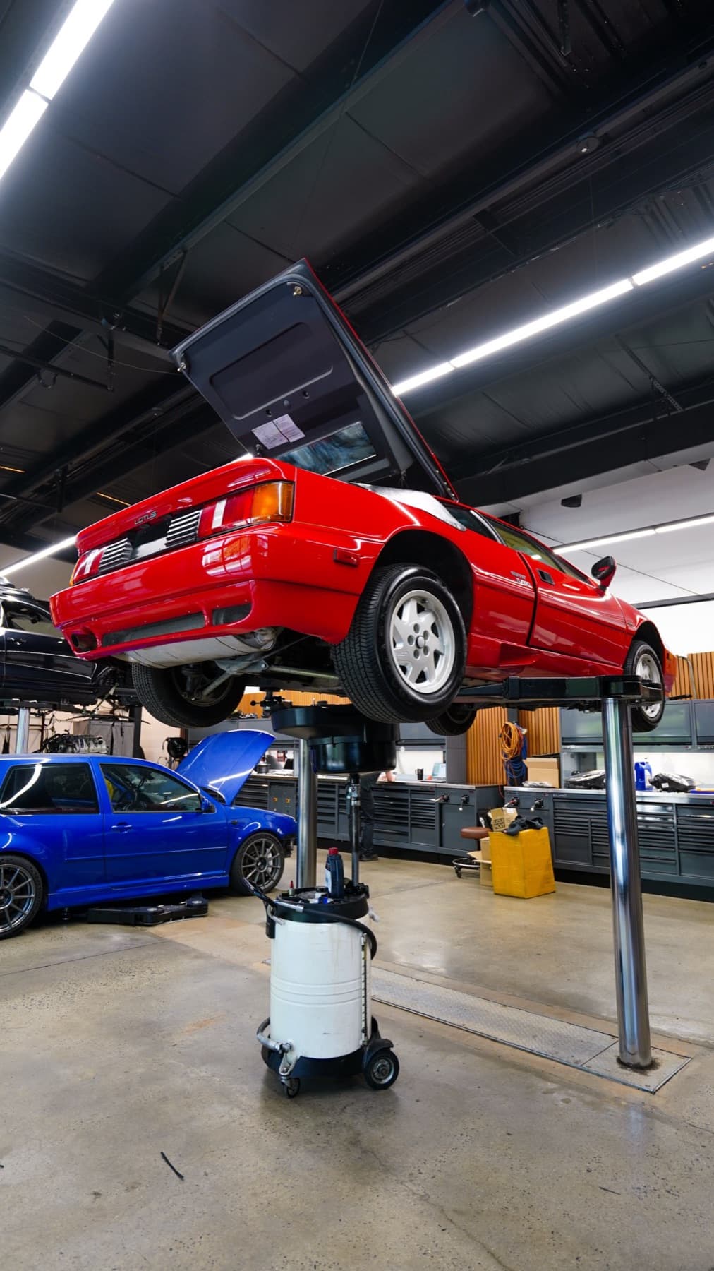 Red car raised on a lift above a blue car