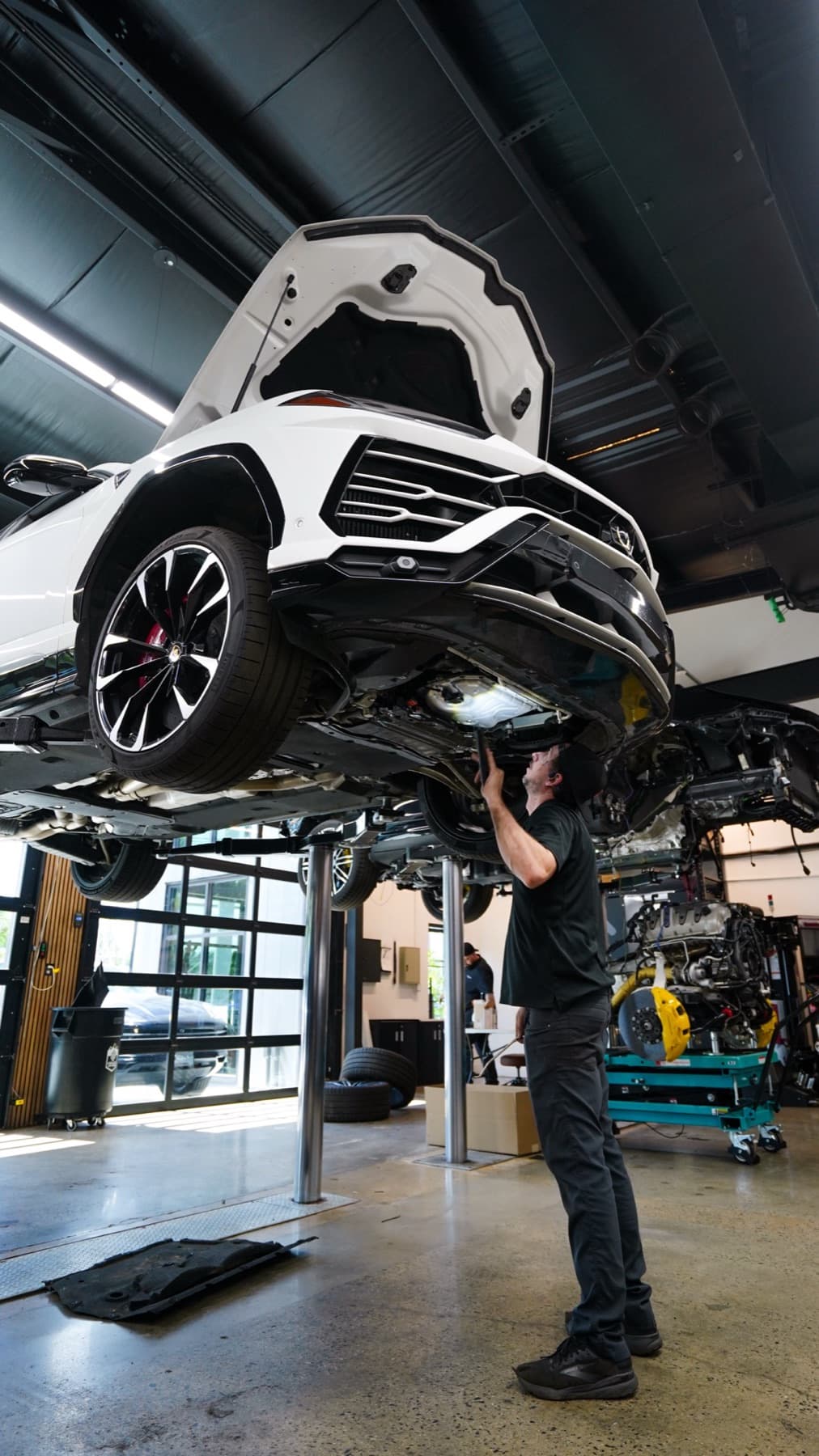 White SUV raised on a lift with a technician underneath