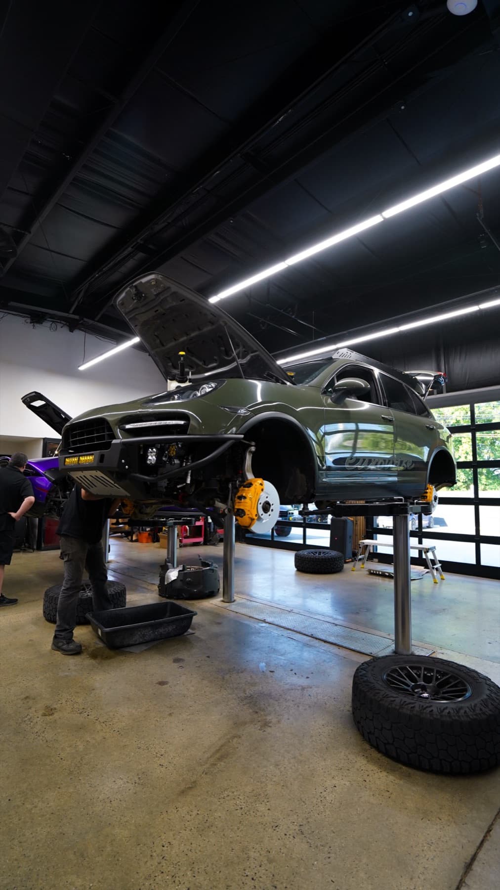 Grey car on a lift with its wheels off