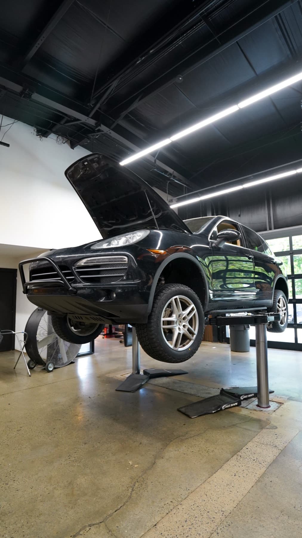 Dark SUV on a lift with its hood open