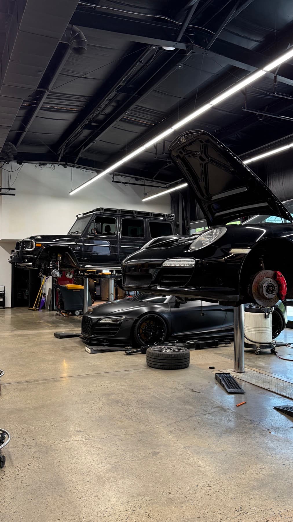 Black car with its hood open in the service bays