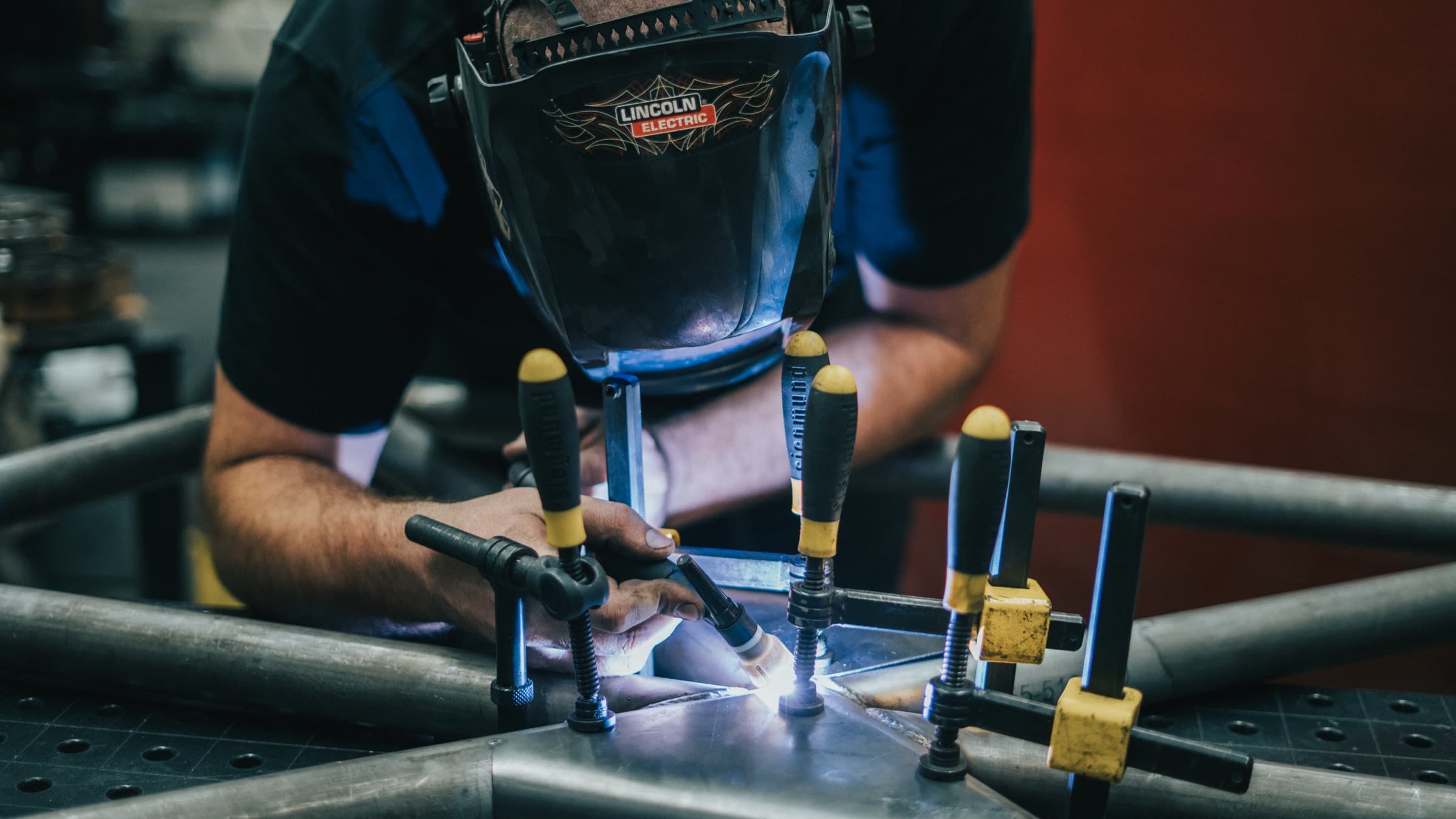 Fabricator welding a clamped tube frame